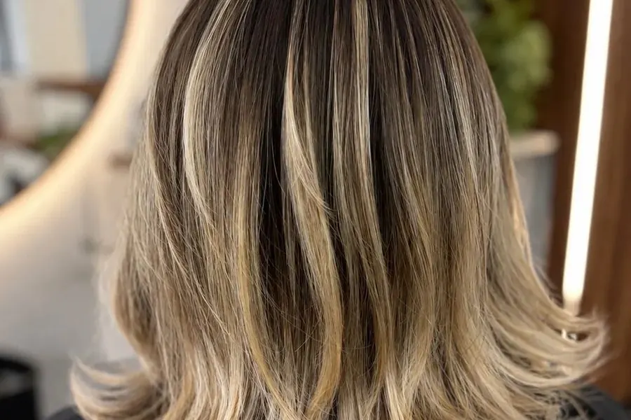 Long blonde balayage with soft root shadow, seen from behind