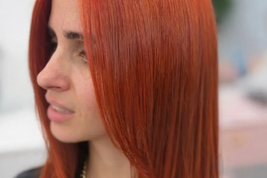 Vivid copper red colour on mid-length hair, side view